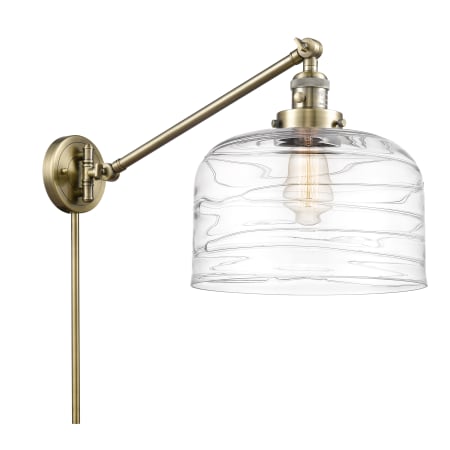 A large image of the Innovations Lighting 237-13-12-L Bell Sconce Antique Brass / Clear Deco Swirl