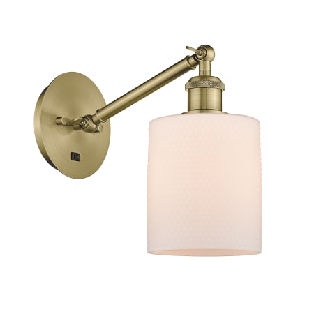 A large image of the Innovations Lighting 317-1W-13-6 Cobbleskill Sconce Antique Brass / Matte White