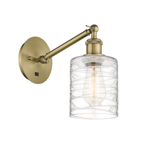 A large image of the Innovations Lighting 317-1W-13-6 Cobbleskill Sconce Antique Brass / Deco Swirl