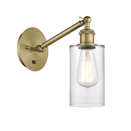 A large image of the Innovations Lighting 317-1W-13-5 Clymer Sconce Antique Brass / Clear