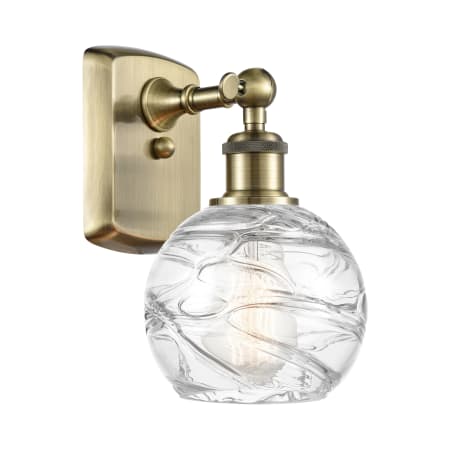 A large image of the Innovations Lighting 516-1W-11-6 Athens Sconce Antique Brass / Clear Deco Swirl