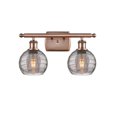 A large image of the Innovations Lighting 516-2W-10-16 Athens Deco Swirl Vanity Antique Copper / Light Smoke Deco Swirl