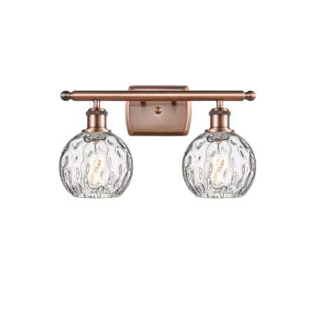 A large image of the Innovations Lighting 516-2W-11-16 Athens Vanity Antique Copper / Clear Water Glass