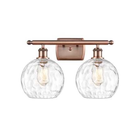 A large image of the Innovations Lighting 516-2W-13-18 Athens Vanity Antique Copper / Clear Water Glass