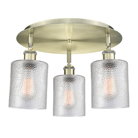 A large image of the Innovations Lighting 516-3C-10-18 Cobbleskill Flush Antique Brass / Clear