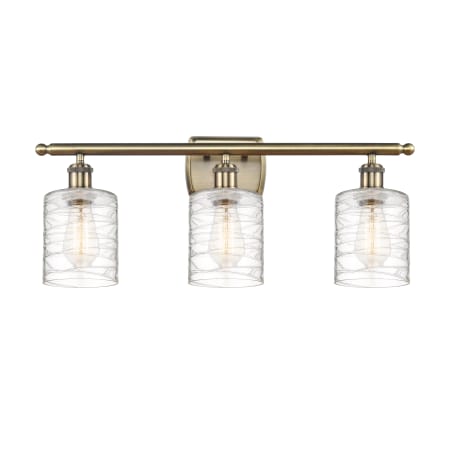 A large image of the Innovations Lighting 516-3W-10-26 Cobbleskill Vanity Antique Brass / Deco Swirl