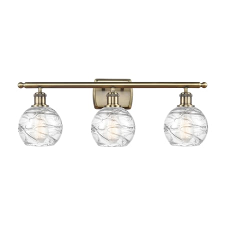 A large image of the Innovations Lighting 516-3W-11-26 Athens Vanity Antique Brass / Clear Deco Swirl