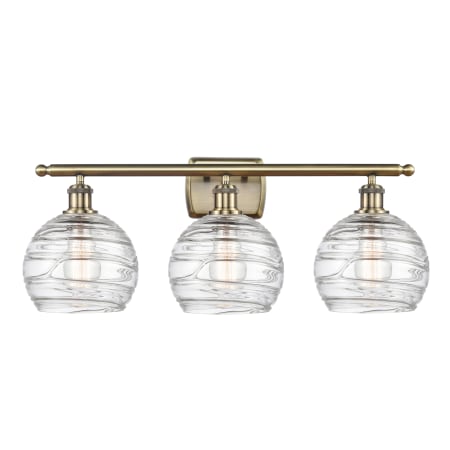 A large image of the Innovations Lighting 516-3W-11-26 Athens Vanity Clear Deco Swirl / Antique Brass