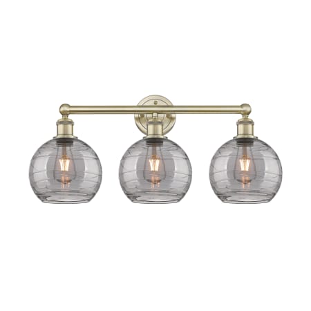 A large image of the Innovations Lighting 616-3W 12 26 Athens Deco Swirl Vanity Antique Brass / Light Smoke Deco Swirl