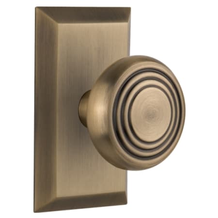 Nostalgic Warehouse Deco Solid Brass Passage Door Knob Set with Studio Rose and 2-3/4" Backset Antique Brass