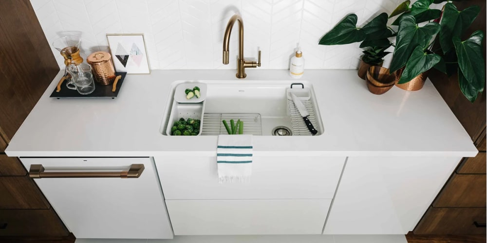 Undermount sink, white counter, gold kitchen faucet.