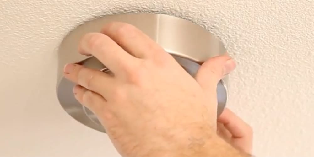 Hands holding canopy in place against ceiling.