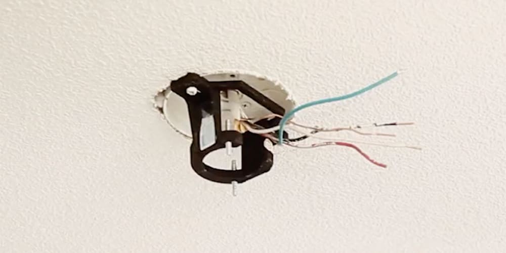 Bracket attached to outlet box with wires exposed.