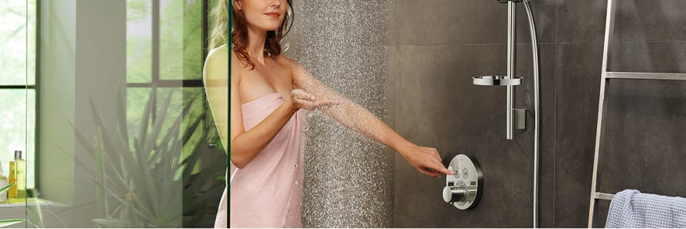 Woman feeling the water spray and adjusting temperature modes, gray tile.