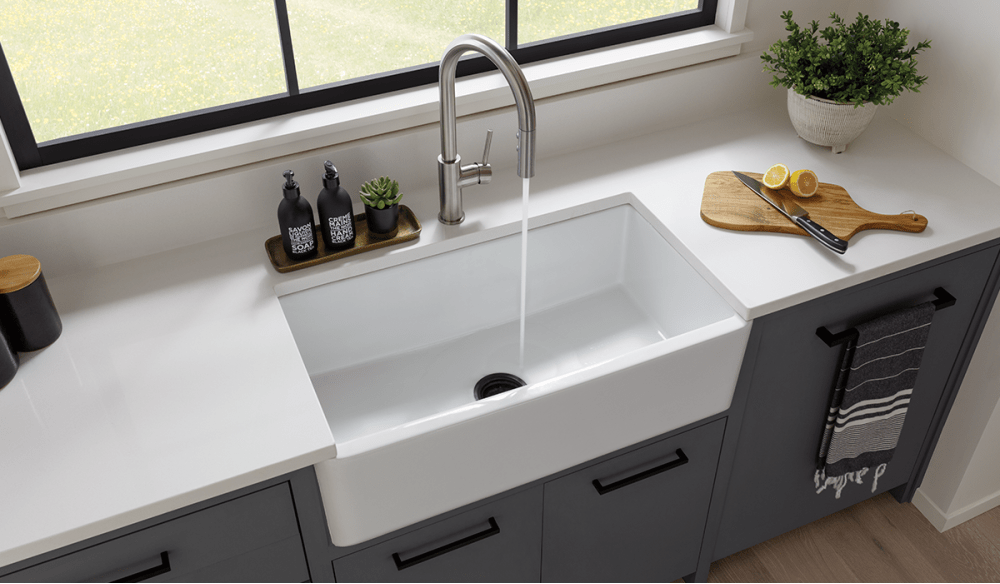 White farmhouse sink, gray cabinets, modern kitchen faucet.