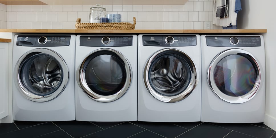 Dryers and washers, black and white with chrome details. White tile.