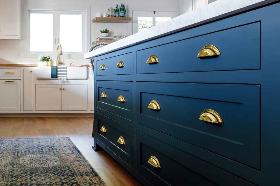 Luxury kitchen with navy blue cabinets, gold cup pulls, gold knobs.