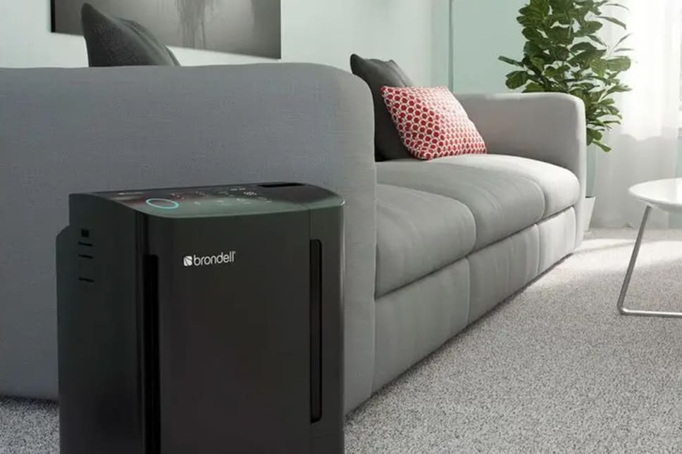 Living room with a black portable air purifier sitting on floor.