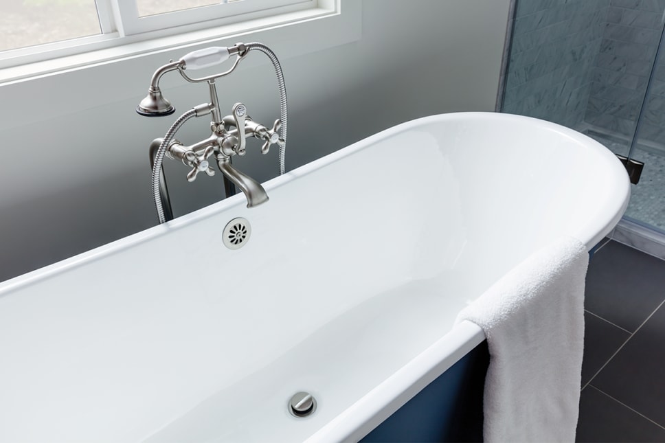 Blue claw foot bathtub with overflow drain in brushed nickel finish.