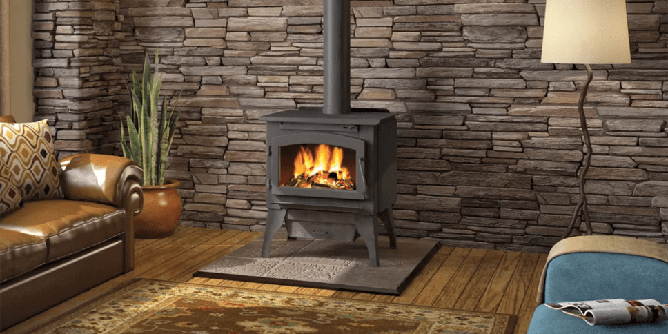 black iron square stove, brown wood floor, tan stucco wall, orange flames.