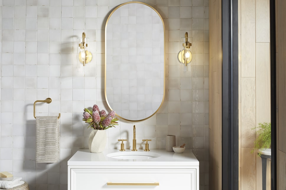 Gold light sconces on either side of bathroom vanity, gold faucet