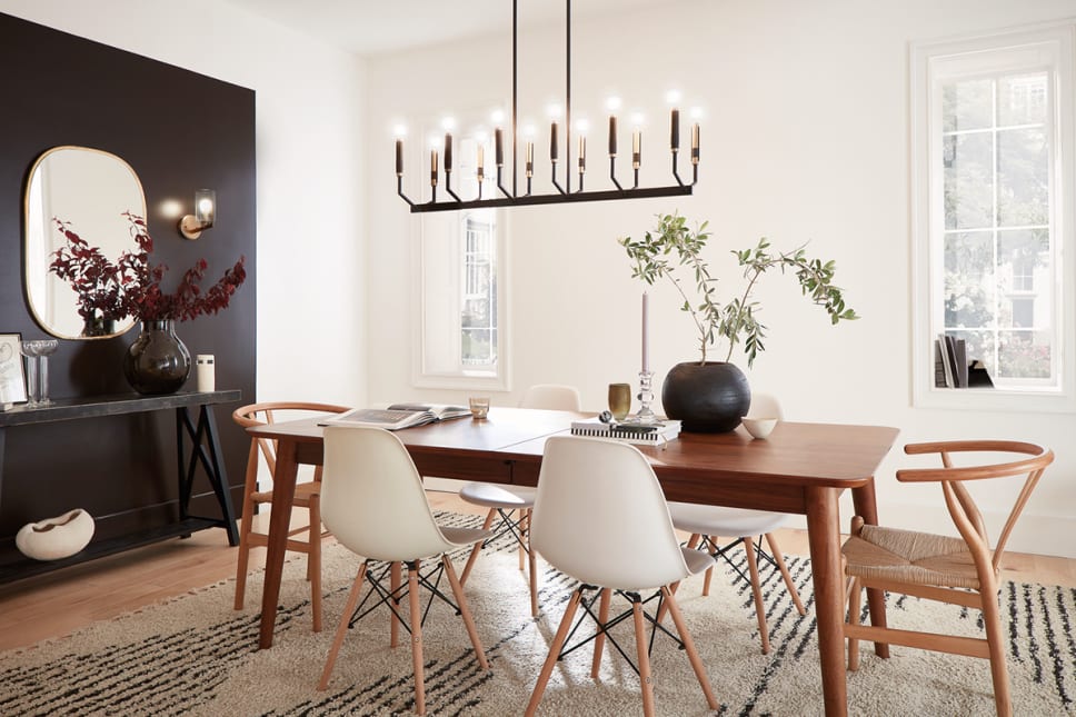 Linear candle chandelier in black and brass finish in modern dining room.